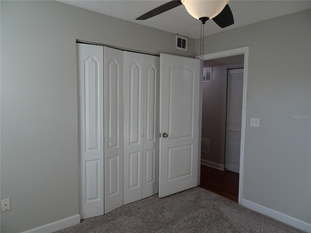 unfurnished bedroom featuring carpet flooring, ceiling fan, a textured ceiling, and a closet