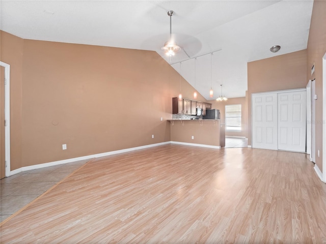 unfurnished living room with a chandelier, light hardwood / wood-style flooring, and high vaulted ceiling