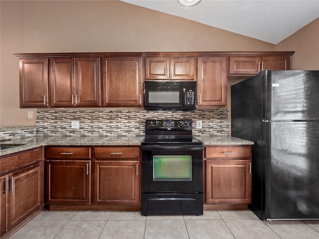 kitchen with light stone counters, vaulted ceiling, black appliances, light tile patterned floors, and backsplash