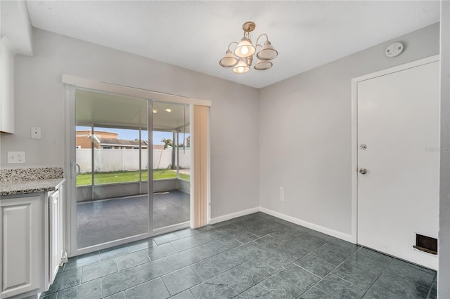 empty room featuring a textured ceiling, an inviting chandelier, and dark tile patterned flooring