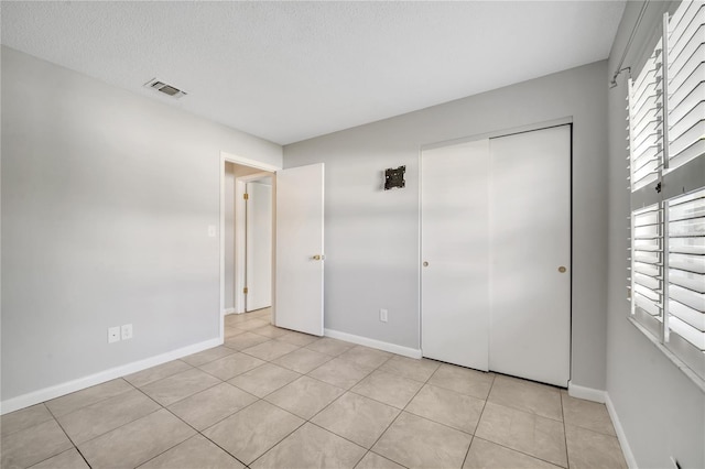 unfurnished bedroom featuring light tile patterned floors, a textured ceiling, and a closet