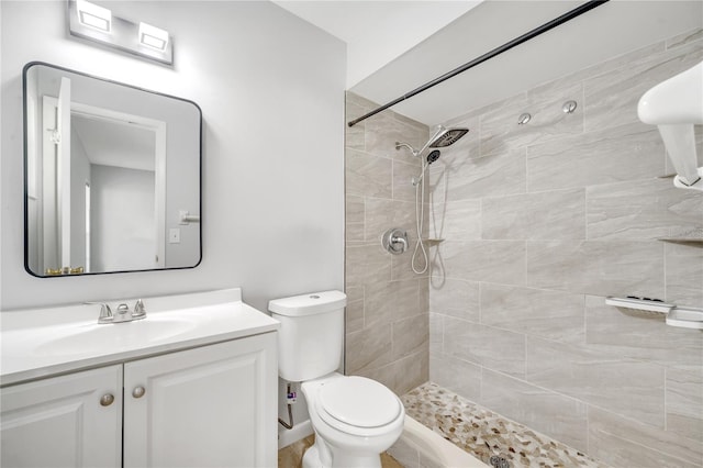 bathroom featuring toilet, vanity, and a tile shower