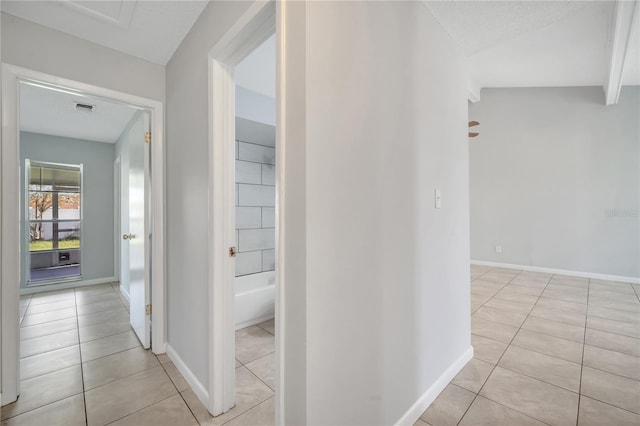 corridor with a textured ceiling, light tile patterned floors, and vaulted ceiling