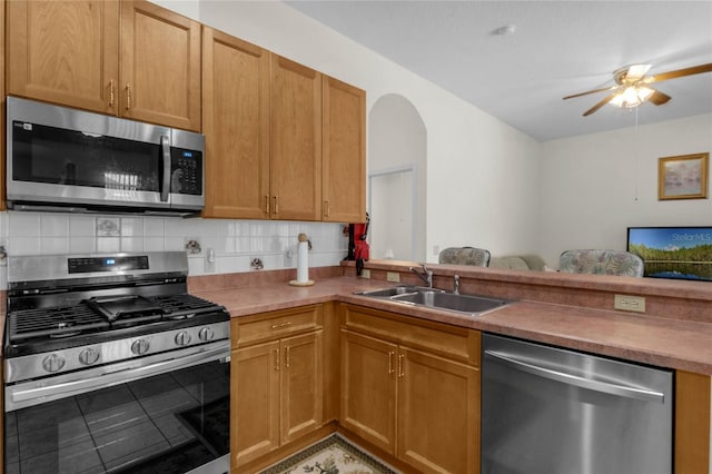 kitchen with decorative backsplash, kitchen peninsula, appliances with stainless steel finishes, and sink