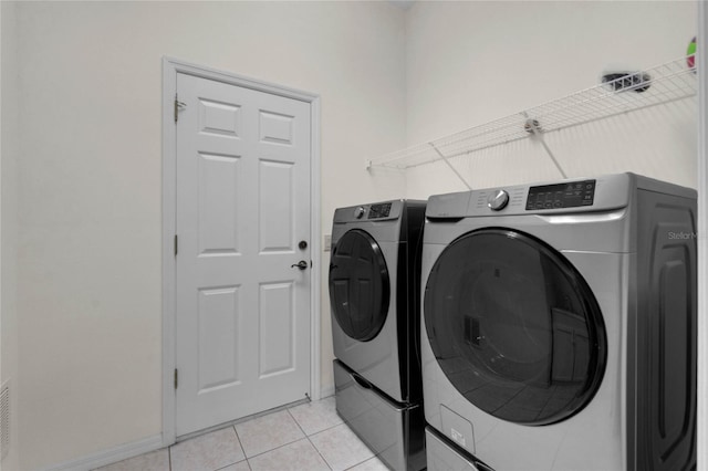 laundry room featuring washer and clothes dryer and light tile patterned floors