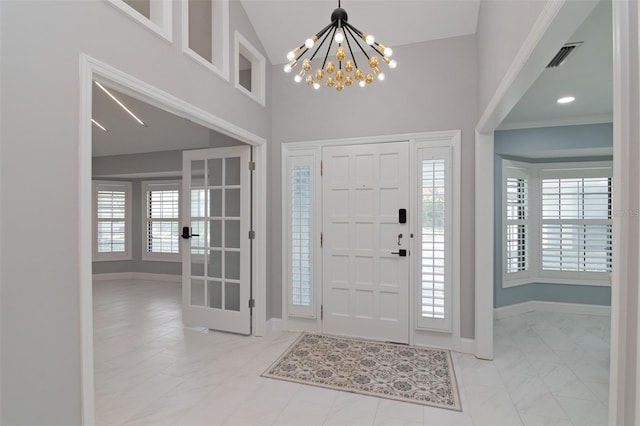 entrance foyer featuring high vaulted ceiling, french doors, a notable chandelier, and crown molding