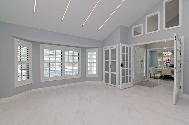 unfurnished room featuring a chandelier, lofted ceiling, and french doors