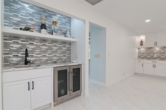 bar with wine cooler, backsplash, sink, and white cabinets