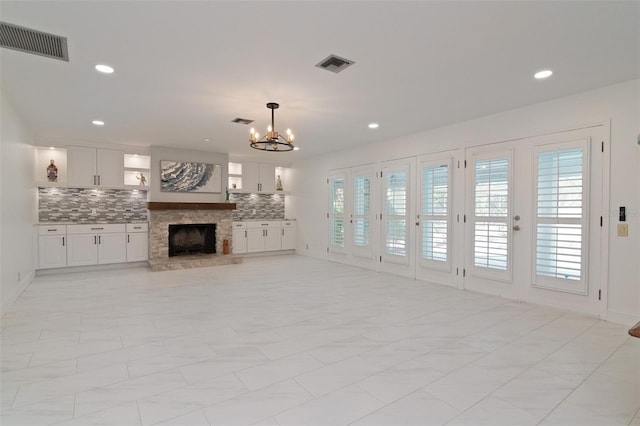 unfurnished living room featuring a chandelier and a fireplace