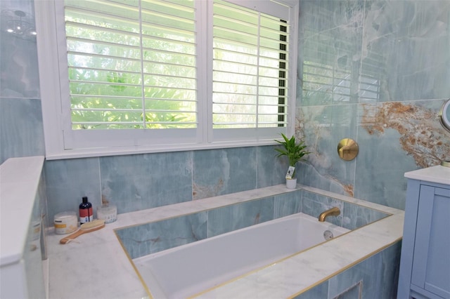 bathroom with a washtub, vanity, and a healthy amount of sunlight