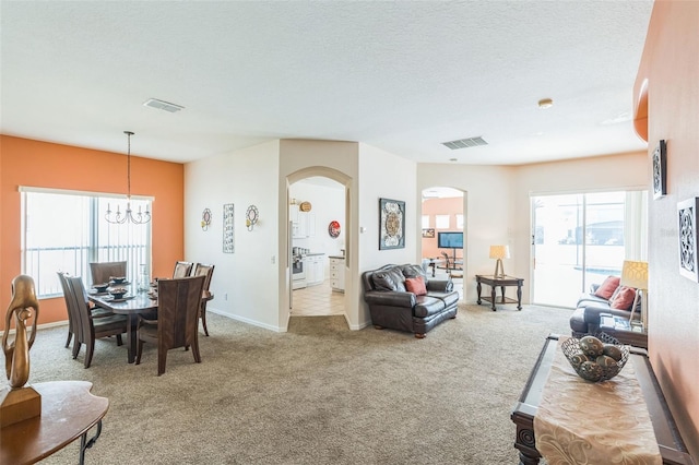 living room featuring a textured ceiling, light carpet, and an inviting chandelier