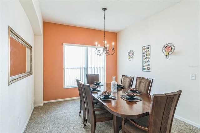 carpeted dining room with an inviting chandelier