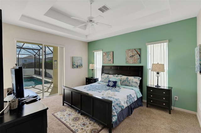 bedroom with ceiling fan, light colored carpet, access to exterior, and a tray ceiling