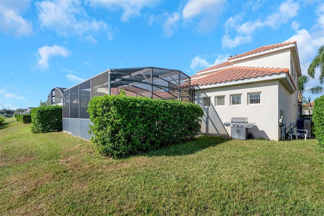 exterior space featuring a yard and glass enclosure