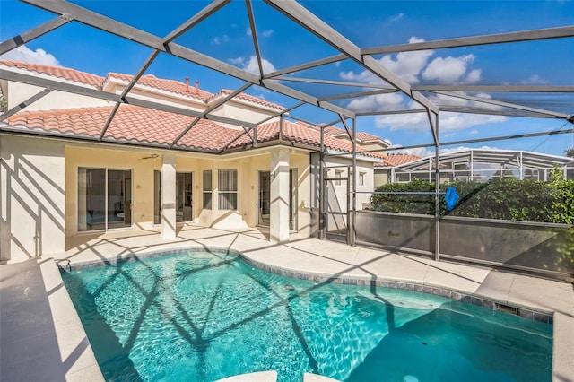 view of swimming pool with ceiling fan, glass enclosure, and a patio area