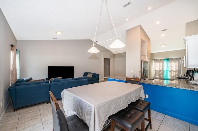 tiled dining space featuring sink and vaulted ceiling