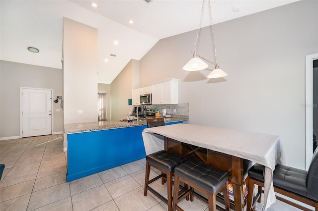 kitchen featuring stainless steel appliances, white cabinetry, kitchen peninsula, pendant lighting, and decorative backsplash