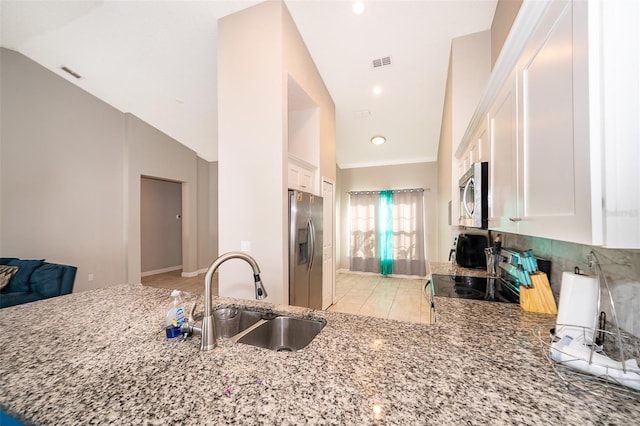 kitchen with white cabinetry, stainless steel appliances, sink, and vaulted ceiling