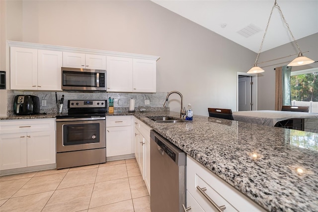 kitchen with stainless steel appliances, stone countertops, high vaulted ceiling, sink, and white cabinets