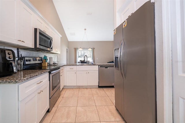 kitchen with appliances with stainless steel finishes, hanging light fixtures, white cabinets, and vaulted ceiling