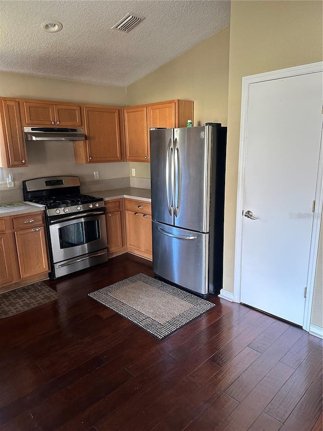 kitchen with dark wood-type flooring, vaulted ceiling, a textured ceiling, and appliances with stainless steel finishes