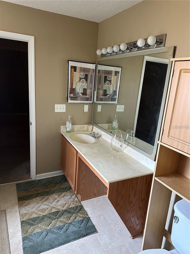 bathroom featuring vanity, a textured ceiling, and toilet