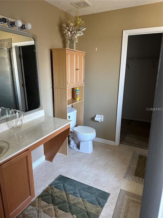 bathroom featuring a shower with door, a textured ceiling, a chandelier, vanity, and toilet