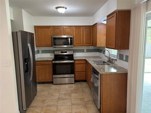 kitchen featuring a wealth of natural light, light stone countertops, appliances with stainless steel finishes, and sink