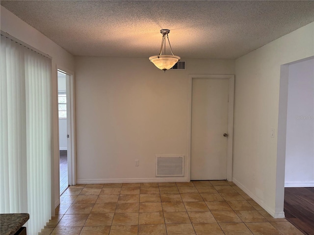 tiled spare room featuring a textured ceiling