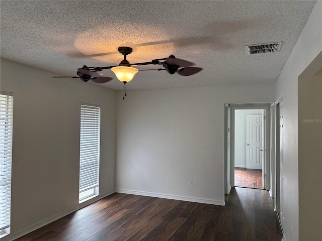 empty room with a textured ceiling, dark hardwood / wood-style floors, and ceiling fan