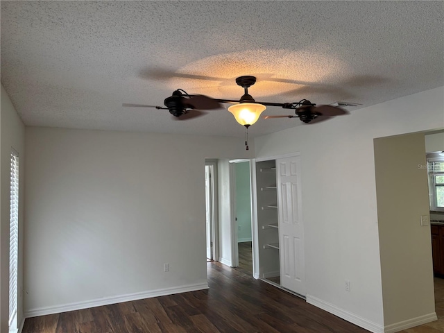 empty room featuring dark wood-type flooring, ceiling fan, and a textured ceiling