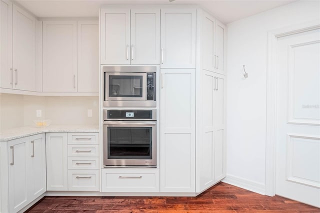 kitchen featuring light stone counters, dark hardwood / wood-style flooring, white cabinets, and stainless steel appliances