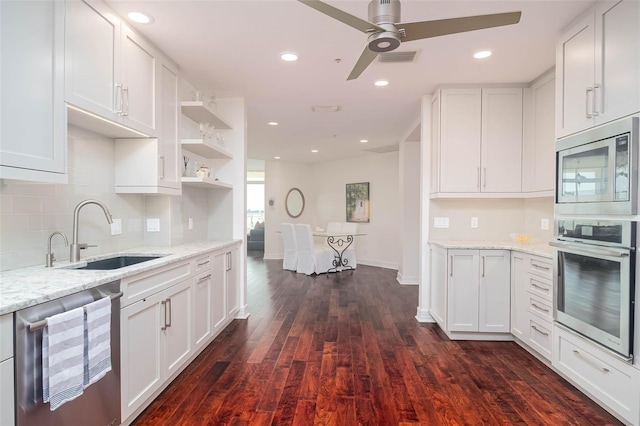 kitchen featuring appliances with stainless steel finishes, light stone counters, dark wood-type flooring, sink, and white cabinetry