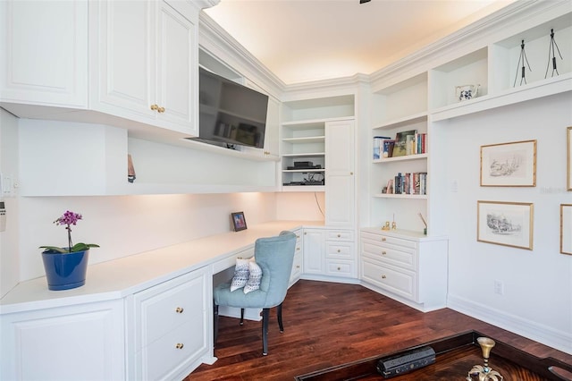 office space with built in shelves, built in desk, dark hardwood / wood-style floors, and ornamental molding