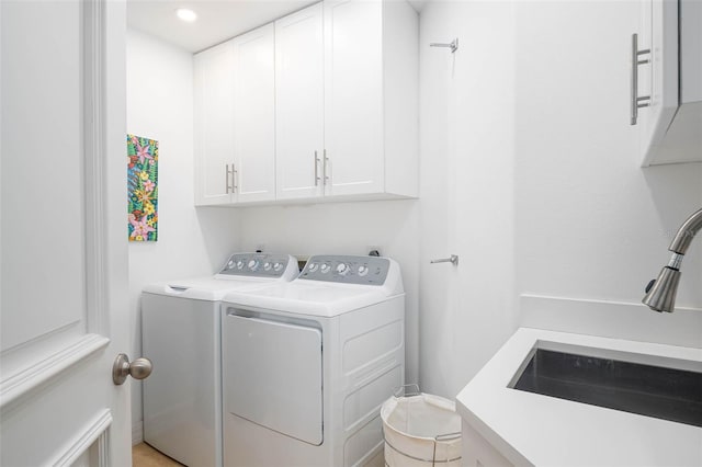 laundry room with cabinets, separate washer and dryer, and sink