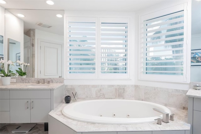 bathroom featuring vanity and tiled tub