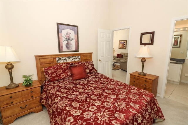 bedroom with ensuite bathroom and light carpet