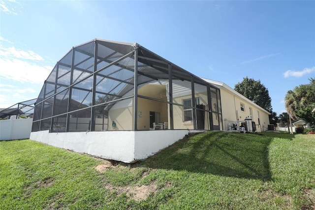 rear view of property with a lawn and glass enclosure