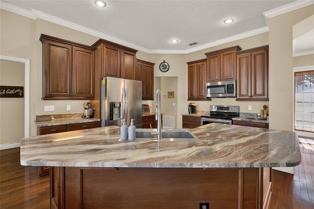 kitchen with a textured ceiling, a large island, ornamental molding, dark hardwood / wood-style floors, and appliances with stainless steel finishes