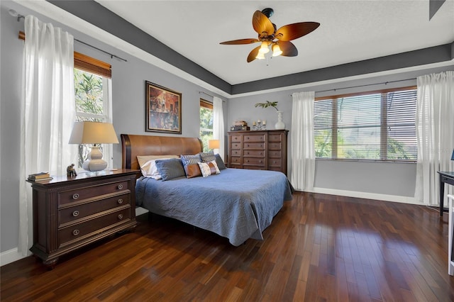 bedroom featuring ceiling fan, multiple windows, and dark hardwood / wood-style flooring