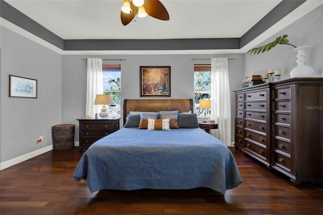 bedroom featuring ceiling fan, multiple windows, and dark hardwood / wood-style floors