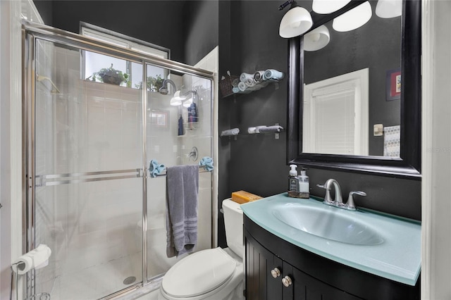 bathroom featuring a shower with door, vanity, and toilet