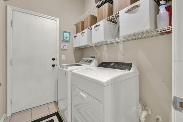 clothes washing area with washing machine and dryer and light tile patterned floors