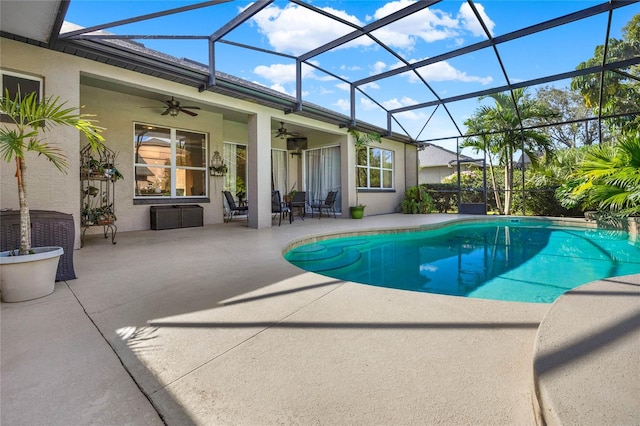 view of swimming pool featuring glass enclosure, ceiling fan, and a patio area