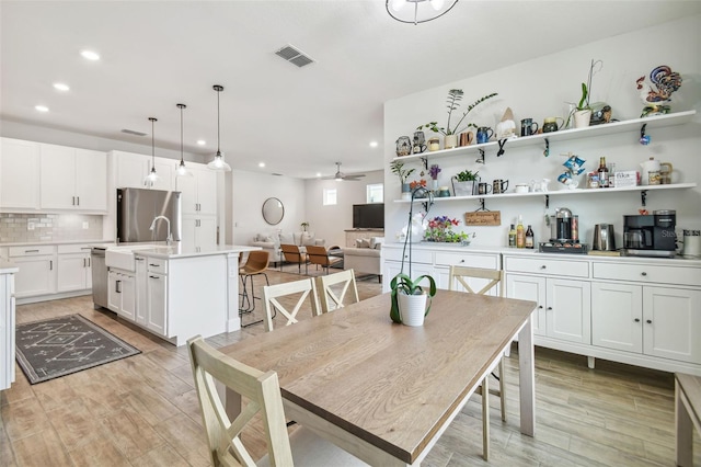 dining space featuring light hardwood / wood-style flooring, ceiling fan, and sink