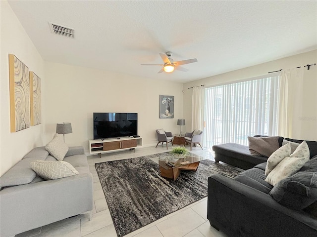 living room with a textured ceiling, ceiling fan, and light tile patterned flooring