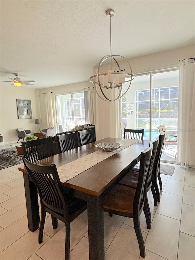 tiled dining room featuring ceiling fan with notable chandelier and a textured ceiling