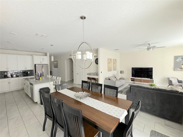 tiled dining room featuring ceiling fan with notable chandelier, a textured ceiling, and sink