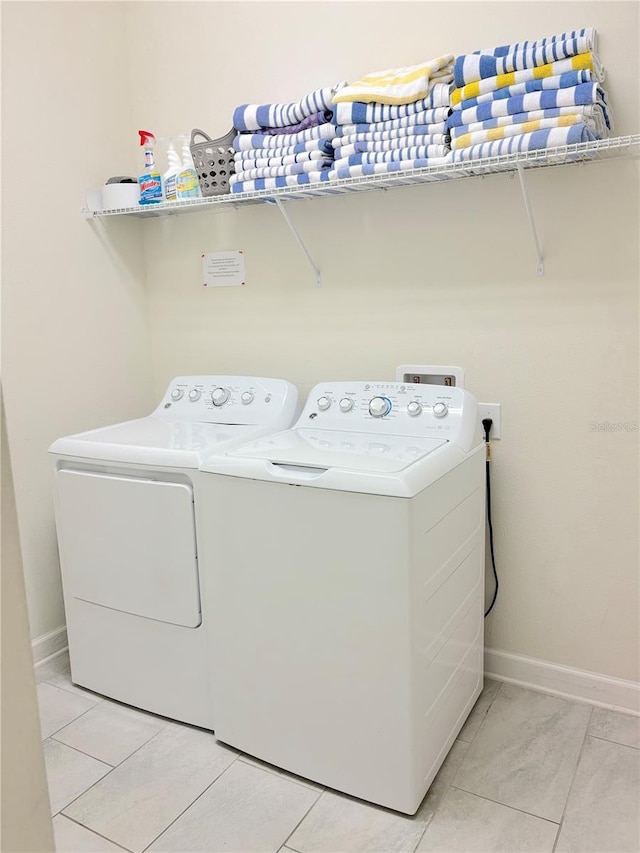 laundry room with washer and dryer and light tile patterned floors