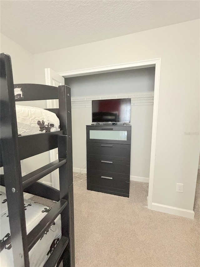 bedroom featuring light colored carpet and a textured ceiling